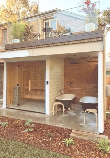The cedar-lined sauna cabin under the deck, lit warm at dusk.